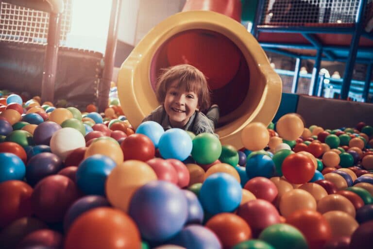 Beispielbild little boy lying pool full colorful balls